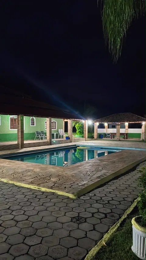 Piscina iluminada à noite, com a varanda acesa ao fundo