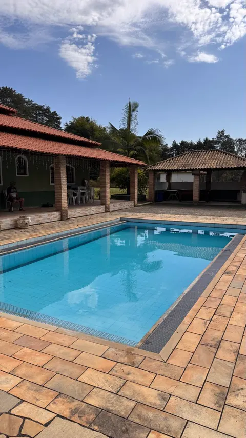 Piscina em dia de sol, com a varanda coberta ao fundo