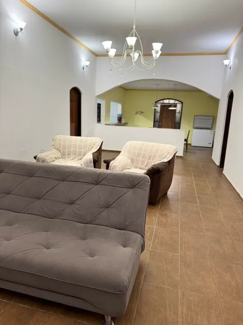 Sala ampla com sofás, arcos e a mesa de jantar ao fundo